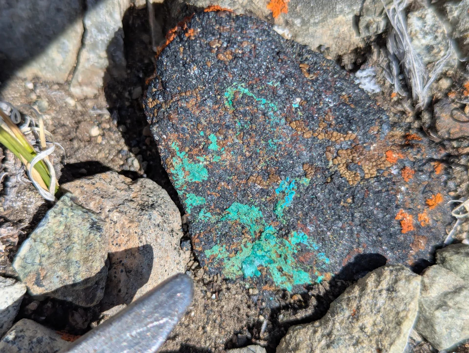 Green copper carbonate on massive magnetite float, hammer tip for scale - copper mineralization traversing the magnetite.