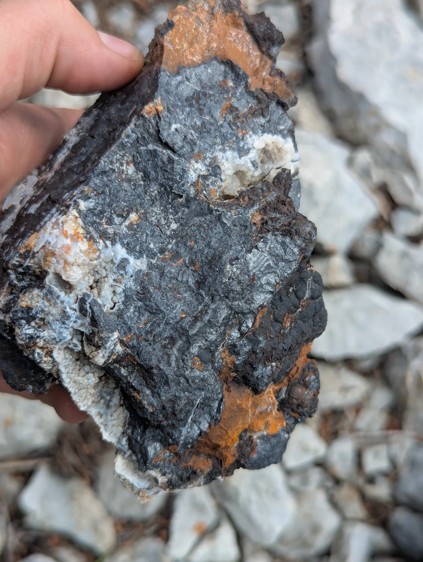 Hand specimen of massive magnetite with limonite and carbonate.