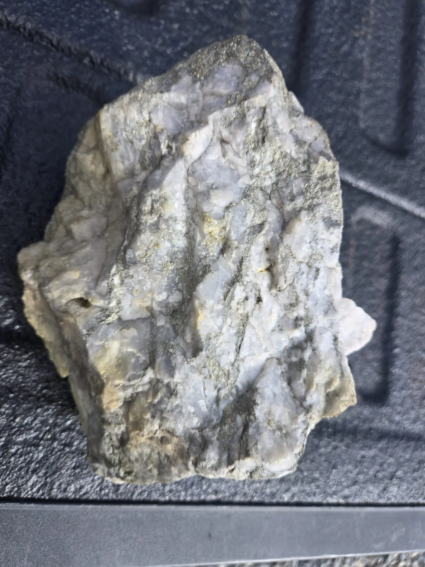 Hand sample of pale grey altered rock with greenish mineralization